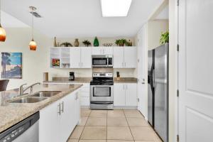 a kitchen with white cabinets and stainless steel appliances at Waterfront condo with private boat slip - best of beach and bay! in South Padre Island