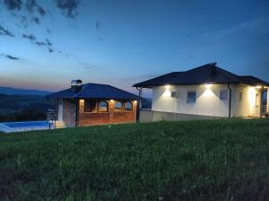una casa en la cima de una colina de hierba por la noche en Vikendica sa bazenom Staša en Banja Luka
