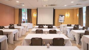 a conference room with white tables and chairs and a screen at Holiday Inn Kenilworth - Warwick, an IHG Hotel in Kenilworth