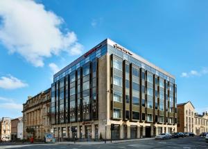 a building on a street next to a road at Hampton by Hilton Glasgow Central in Glasgow