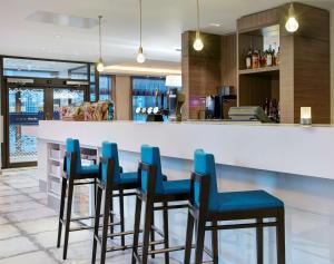 a kitchen with a bar with blue chairs at Hampton by Hilton Glasgow Central in Glasgow