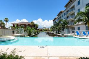 a swimming pool at a resort with chairs and a building at Waterfront condo with private boat slip - best of beach and bay! in South Padre Island