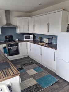 a kitchen with white cabinets and a white refrigerator at Bob's Bunkhouse in Troed-y-rhiw