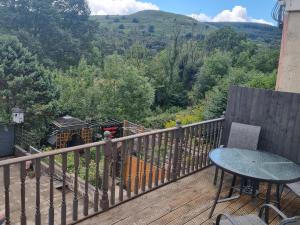 a balcony with a table and a tractor in the woods at Bob's Bunkhouse in Troed-y-rhiw