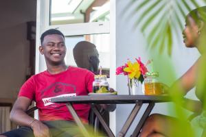 a man sitting at a table with two drinks at Cambria Hotel in Nosy Be