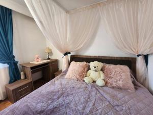 um urso de peluche sentado em cima de uma cama em Apartament liniștit La Pădure em Piteşti