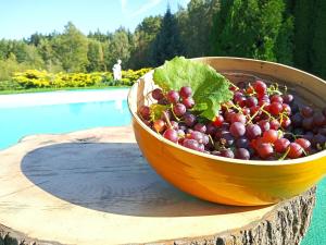 a wooden bowl of grapes sitting on a table next to a pool at Agroturystyka "Dworek u Pelców" in Ryn