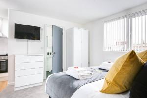 Dormitorio blanco con cama con almohada amarilla en SCA - Luxurious Studio - VS5 en Wolverhampton