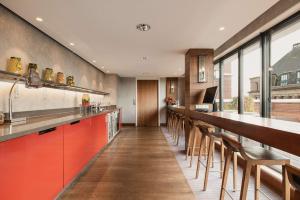 a large kitchen with a long bar with wooden stools at Hilton The Hague in The Hague