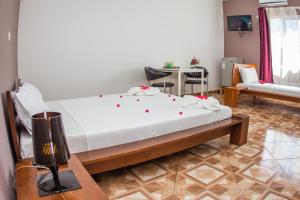 a bedroom with a bed and a chair and a table at Cambria Hotel in Nosy Be