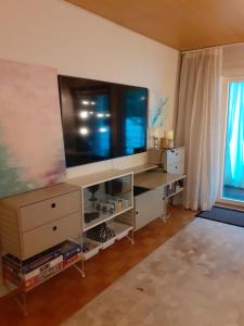 ein Wohnzimmer mit einem großen TV und einer Kommode in der Unterkunft Ann's terraced house with sauna in Vantaa