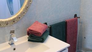 a bathroom with towels on a sink and a mirror at APT Nazaré in Nazaré +6 photos