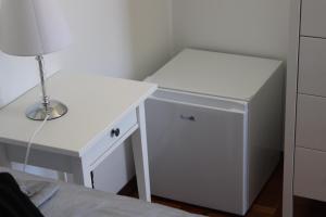 Zimmer mit einem weißen Schreibtisch und einem kleinen Kühlschrank. in der Unterkunft APT Nazaré in Nazaré