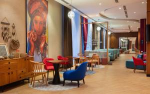 a waiting room with chairs and tables and a painting at Hampton By Hilton Turkistan in Türkistan