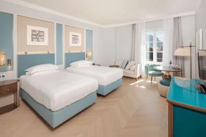a hotel room with two beds and a desk at Hilton Imperial Dubrovnik in Dubrovnik