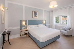 a bedroom with a large bed and a chair at Hilton Imperial Dubrovnik in Dubrovnik