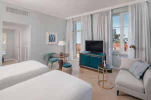 a hotel room with a bed and a tv and a couch at Hilton Imperial Dubrovnik in Dubrovnik