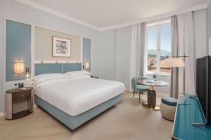 a bedroom with a large bed and a table and a chair at Hilton Imperial Dubrovnik in Dubrovnik