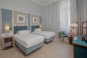 a hotel room with two beds and a desk at Hilton Imperial Dubrovnik in Dubrovnik