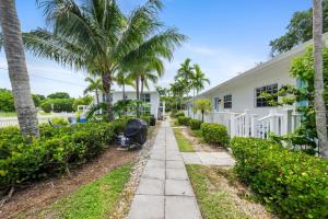 a walkway in front of a white house with palm trees at Seahorse Beach Bungalows in Fort Pierce