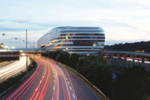 a large building on a highway with cars on it at Hilton Frankfurt Airport in Frankfurt/Main