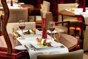a table with two plates of food and wine glasses at Hilton Frankfurt Airport in Frankfurt/Main