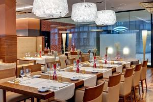 a dining room with tables and chairs and chandeliers at Hilton Frankfurt Airport in Frankfurt/Main