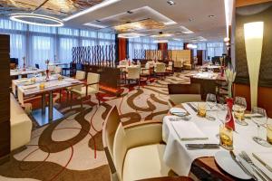 a dining room with white tables and chairs and a restaurant at Hilton Frankfurt Airport in Frankfurt/Main