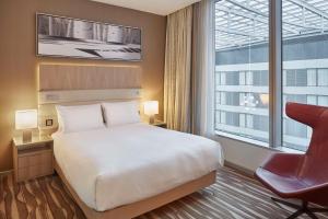 a hotel room with a bed and a chair and a window at Hilton Frankfurt Airport in Frankfurt/Main