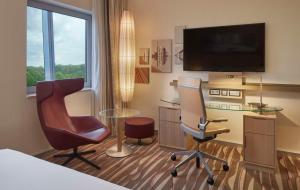 a hotel room with a desk and two chairs and a television at Hilton Frankfurt Airport in Frankfurt/Main