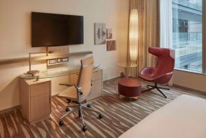 a hotel room with a desk and a chair and a television at Hilton Frankfurt Airport in Frankfurt/Main