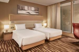 a hotel room with two beds and a chair at Hilton Frankfurt Airport in Frankfurt/Main