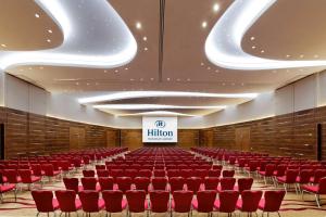 a lecture hall with red chairs and a stage at Hilton Frankfurt Airport in Frankfurt/Main