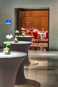 a dining room with tables and red chairs at Hilton Frankfurt Airport in Frankfurt/Main