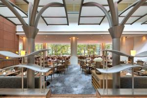 - une salle à manger avec des tables, des chaises et de grandes fenêtres dans l'établissement Hilton Frankfurt City Centre, à Francfort-sur-le-Main
