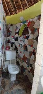 a bathroom with a toilet and a mosaic wall at Omnia Resort in Mtwapa