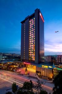 a lit up building with a plane flying over a city at Hilton Garden Inn Istanbul Atatürk Airport in Istanbul