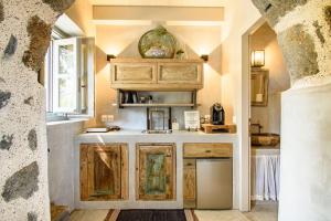 a kitchen with wooden cabinets and a sink at Pavlaina Complex of Traditional Residences in Nisyros. Enjoy the garden and the Sea View in Emporeiós