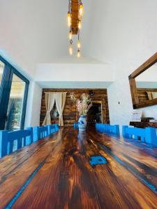 un comedor con una gran mesa de madera y sillas azules en The Hut Retreat, en Fîntînele