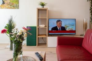 a living room with a tv and a red couch at Balcony Oasis Wilhelminenberg in Vienna