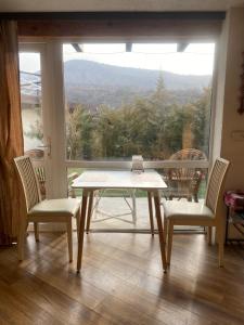 stół i krzesła w pokoju z dużym oknem w obiekcie Dobri Dom w mieście Ałma-Ata