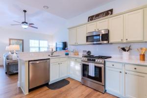 a kitchen with white cabinets and a stove top oven at Calypso Cottage in Bluffton