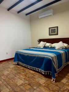 a bedroom with a bed with a blue blanket at Hotel casa teresa café galería in Juchitán de Zaragoza