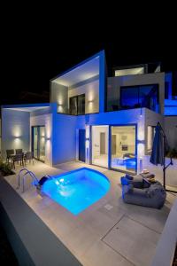 une villa avec une piscine la nuit dans l'établissement White Cliff Luxury Suites by A&D Properties, à Pórto Ráfti