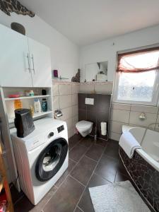 a bathroom with a washing machine and a toilet at Ferienwohnung Nähe Montabaur "Im Herzen des Westerwalds" 