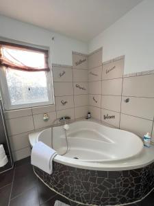 a bath tub in a bathroom with words on the wall at Ferienwohnung "Im Herzen des Westerwalds" in Ettinghausen +22 photos