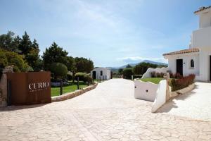 une allée menant à un bâtiment avec des montagnes en arrière-plan dans l'établissement Sulià House Porto Rotondo, Curio Collection by Hilton, à Porto Rotondo