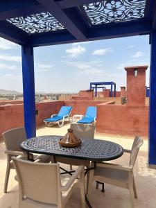eine Terrasse mit einem Tisch und Stühlen auf dem Dach in der Unterkunft Vizir Center Appartement avec solarium et accès offert au Parc de loisirs in Dar Caïd Layadi