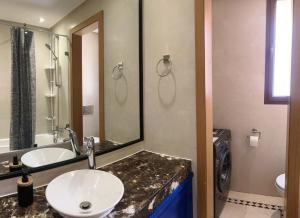 ein Badezimmer mit Waschbecken und Spiegel in der Unterkunft Vizir Center Appartement avec solarium et accès offert au Parc de loisirs in Dar Caïd Layadi + 11 Fotos