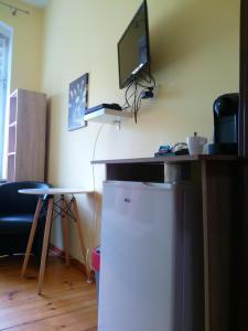 a room with a refrigerator and a desk with a television at Hostel Tulip - pokój 6 ze wspólną łazienką i kuchnią in Szczecin